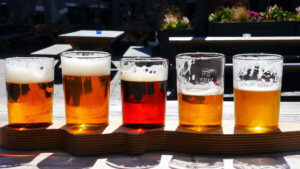 Fünf Gläser mit Bier leuchten verführerisch im Sonnenschein. Von einigen ist schon etwas getrunken worden. Vermutlich eine Verkostung selbst gebrauter Biere. Lecker!